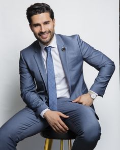 a man in a suit and tie sitting on a stool