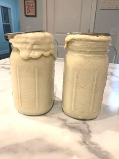 two mason jars filled with cream sitting on top of a counter