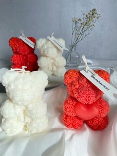 three red and white teddy bears sitting next to each other on top of a table