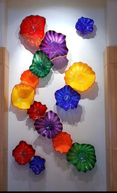 colorful glass flowers are hanging on the wall