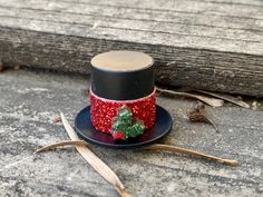 a small top hat with red sequins and a green tree decoration on it