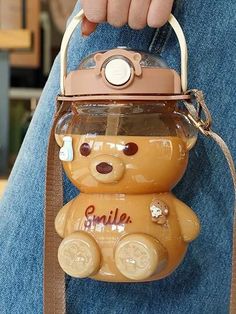 a person holding a brown teddy bear with a camera on it's back pocket