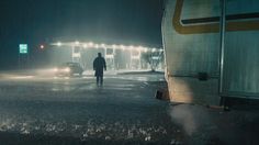 a man standing in the middle of a parking lot at night with his back to the camera