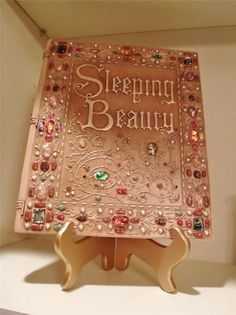 a pink book sitting on top of a wooden stand next to a white box with beads