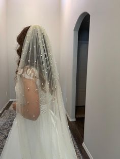 a woman in a wedding dress is looking at herself in the mirror while wearing a veil