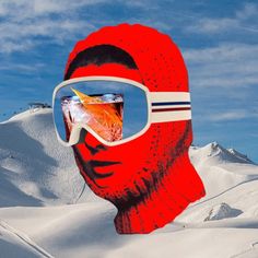 a man's face with sunglasses and a drink in his mouth on top of snow covered mountains