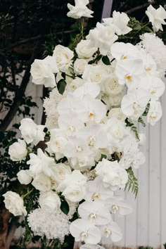 white flowers and greenery are hanging from a pole