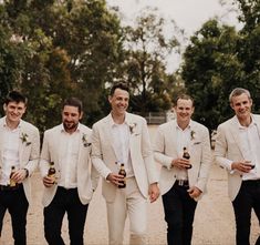 a group of men standing next to each other holding beer bottles