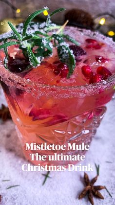 a pink cocktail garnished with cranberries and mint