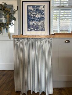 a kitchen counter with a blue and white striped curtain hanging from it's side