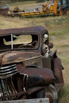 an old rusted truck with a skeleton sitting in the driver's side window