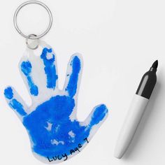 a blue handprinted keychain sitting next to a white marker and pen