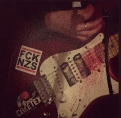 a close up of a person playing an electric guitar with stickers on the body