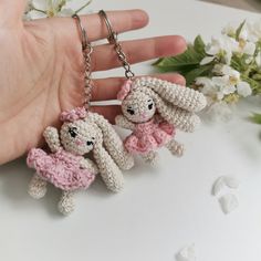 two tiny crocheted bunnies hanging from a hand