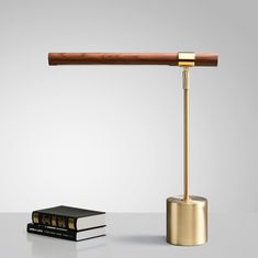 a table lamp with a book on it and a wooden stick in front of it