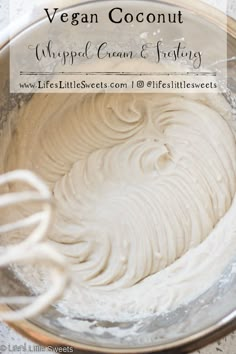 a bowl filled with whipped cream next to a whisk on top of a table