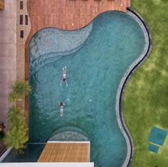 two people are swimming in the pool next to some grass and a building with a sign on it