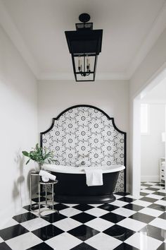 a black and white checkered floor with a bathtub in the center, lights above it