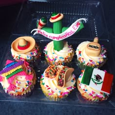 cupcakes decorated with mexican flags and decorations in a clear plastic tray on a table