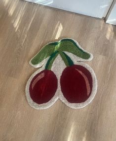 a pair of cherries is on the floor next to a door mat that has two cherries on it