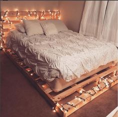 a bed made out of pallets with lights around it