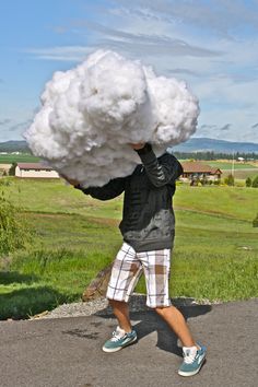 a man is holding cotton floss on his head while walking through the grass in front of him