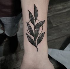 a black and white photo of a leaf tattoo on the wrist, with an arrow in the center