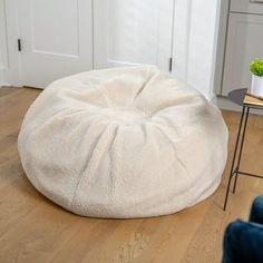 a white bean bag chair sitting on top of a wooden floor next to a table