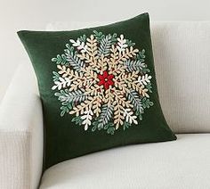 a green pillow with a snowflake design on it sitting on a white couch