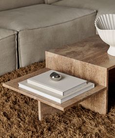 a coffee table sitting on top of a shaggy rug next to a white vase and book