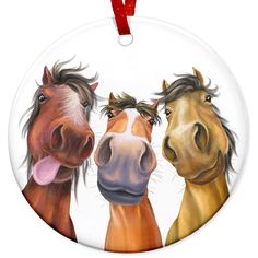 three horses standing next to each other on a round ornament with red ribbon