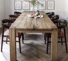 a wooden table with chairs around it in front of pictures on the wall behind it