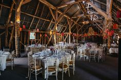 the inside of a barn with tables and chairs set up for a formal dinner or function