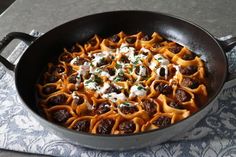 a skillet filled with lots of food on top of a table next to a napkin