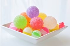 a bowl filled with lots of different colored candies on top of a white table