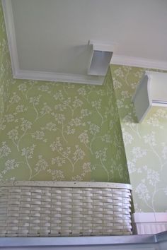 the corner of a room with green wallpaper and white trim on the ceiling above a radiator