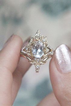 a woman's hand holding an engagement ring with a white diamond in the center