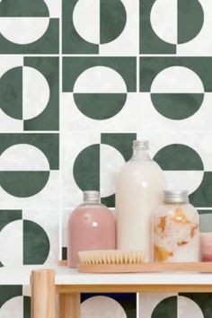 a shelf with bottles and soaps on it in front of a patterned wallpaper