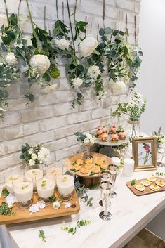 the table is set up with desserts and flowers hanging from the brick wall behind it