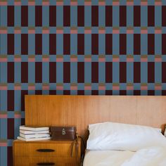 a bed sitting next to a wooden dresser under a blue and red plaid wallpaper