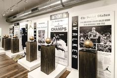 an exhibit room with wooden pedestals and sports memorabilia on the walls, along with posters in black and white