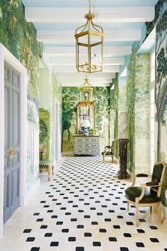 the hallway is decorated with green and white wallpaper, an ornate chandelier, and checkered flooring