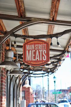 a sign that says main street meats hanging from the side of a brick building