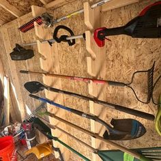 there are many different types of tools hanging on the wall in this shed, including shovels and rakes