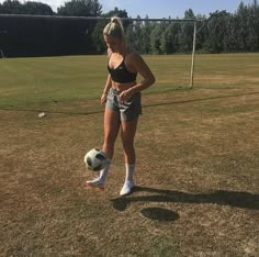 a woman standing on top of a grass covered field with a soccer ball in her hand