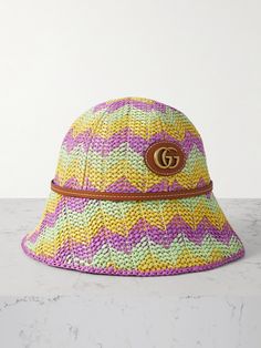 Gucci's bucket hat is made from pastel-colored straw that's woven to create chevron stripes, ensuring it will add a splash of fun to your warm-weather wardrobe. It's lined in soft twill for a comfortable fit and has brown leather trims. Match your jewelry to the gold-tone 'GG' logo embellishment. Designer Brimmed Beach Hats, Spring Straw Bucket Hat, Designer Short-brimmed Hats For Spring, Designer Bucket Hat For Spring, Designer Beach Hats For Spring, Gucci Short Brim Summer Hats, Designer Curved Brim Hat For Spring, Spring Bucket Straw Hat, Designer Bucket Hat For Beach