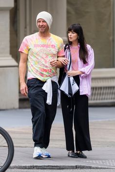 a man and woman are walking down the street with one holding his hand on her hip