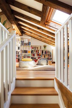 a room with stairs leading up to a bed and bookshelf in the background