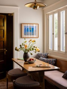 a vase with flowers on top of a wooden table in front of a couch and window