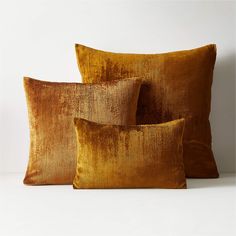 three gold velvet pillows stacked on top of each other